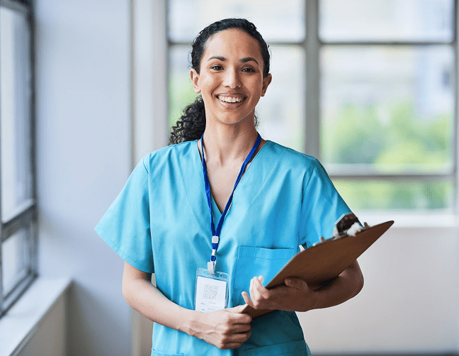 Smiling nurse in blue scrubs holding clipboard