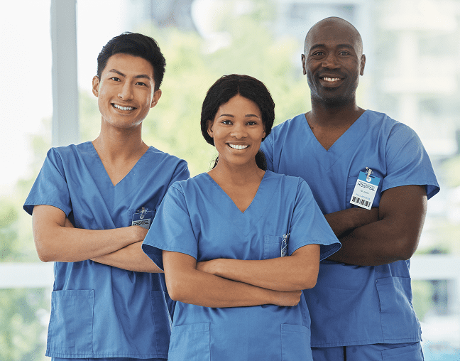Three smiling healthcare workers in blue scrubs