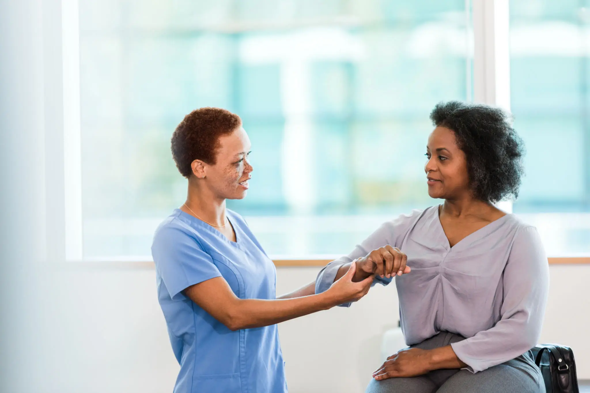 Nurse checking patient's pulse in clinic