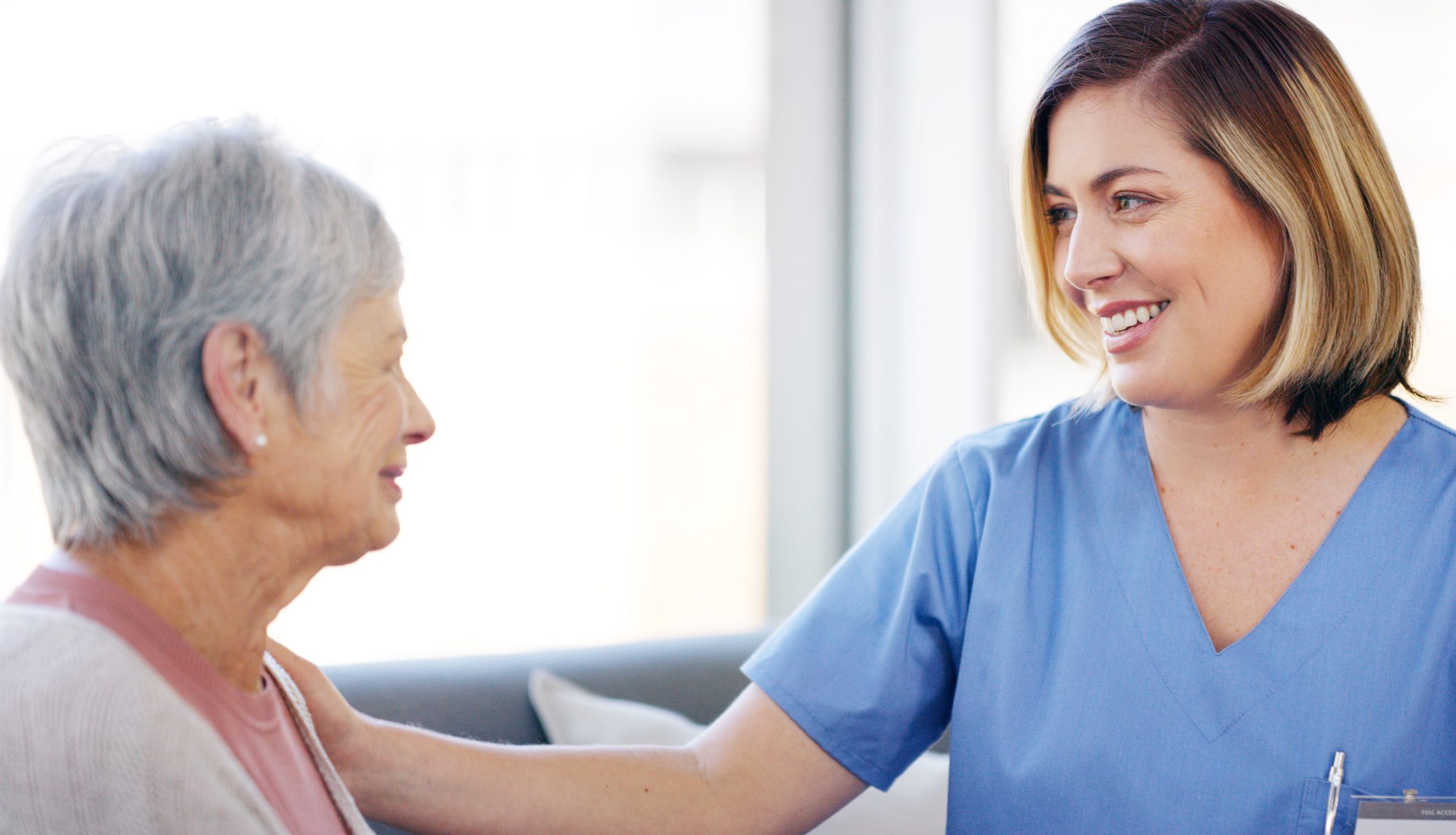 Nurse smiling and comforting elderly woman