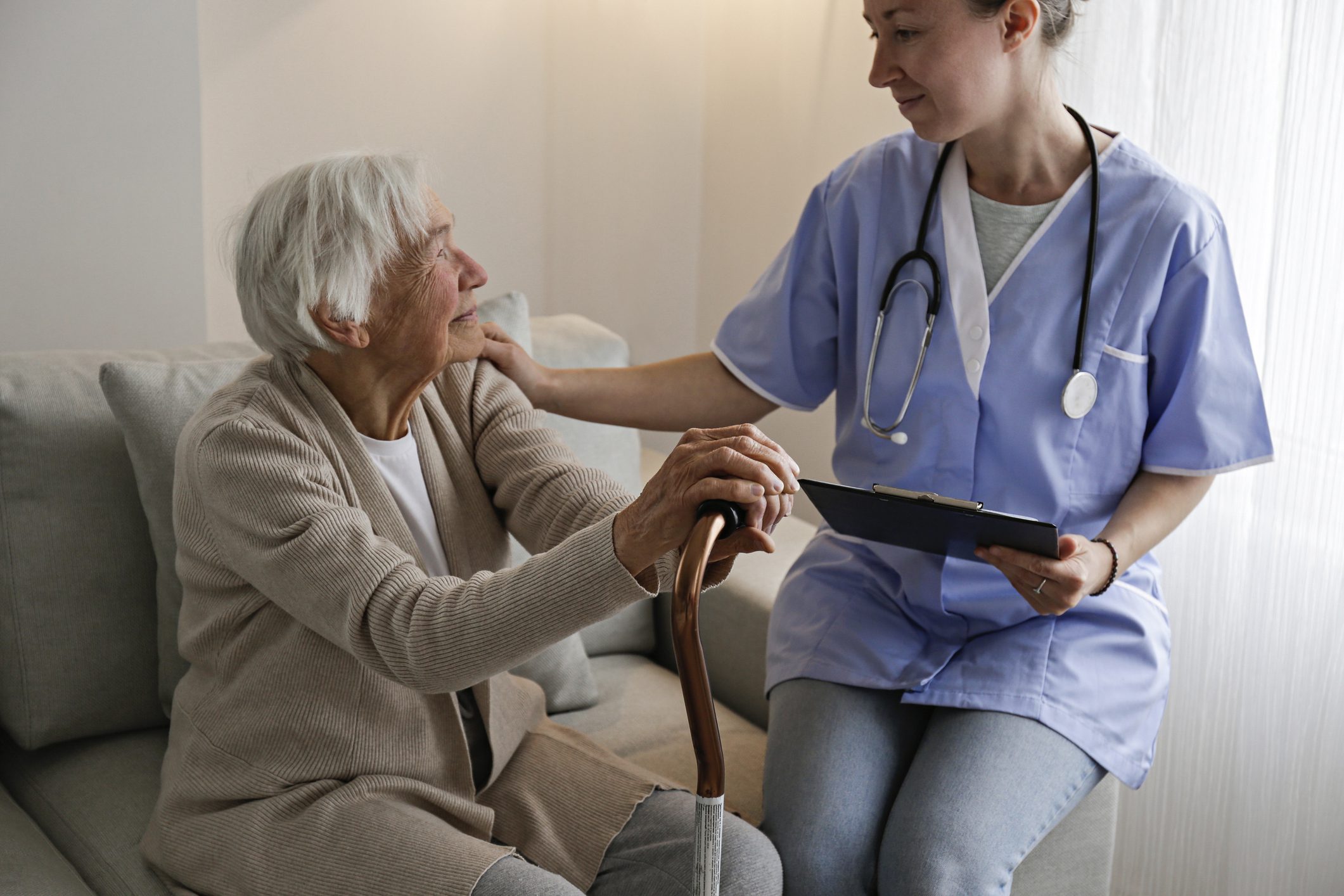 Nurse comforting elderly woman during home visit