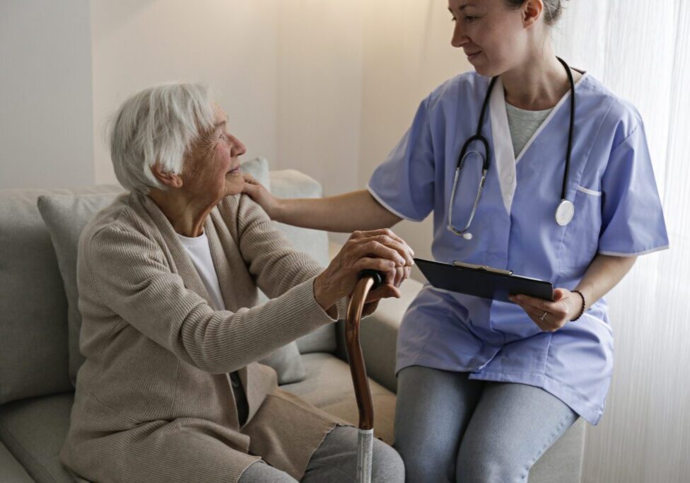 Nurse comforting elderly woman during home visit