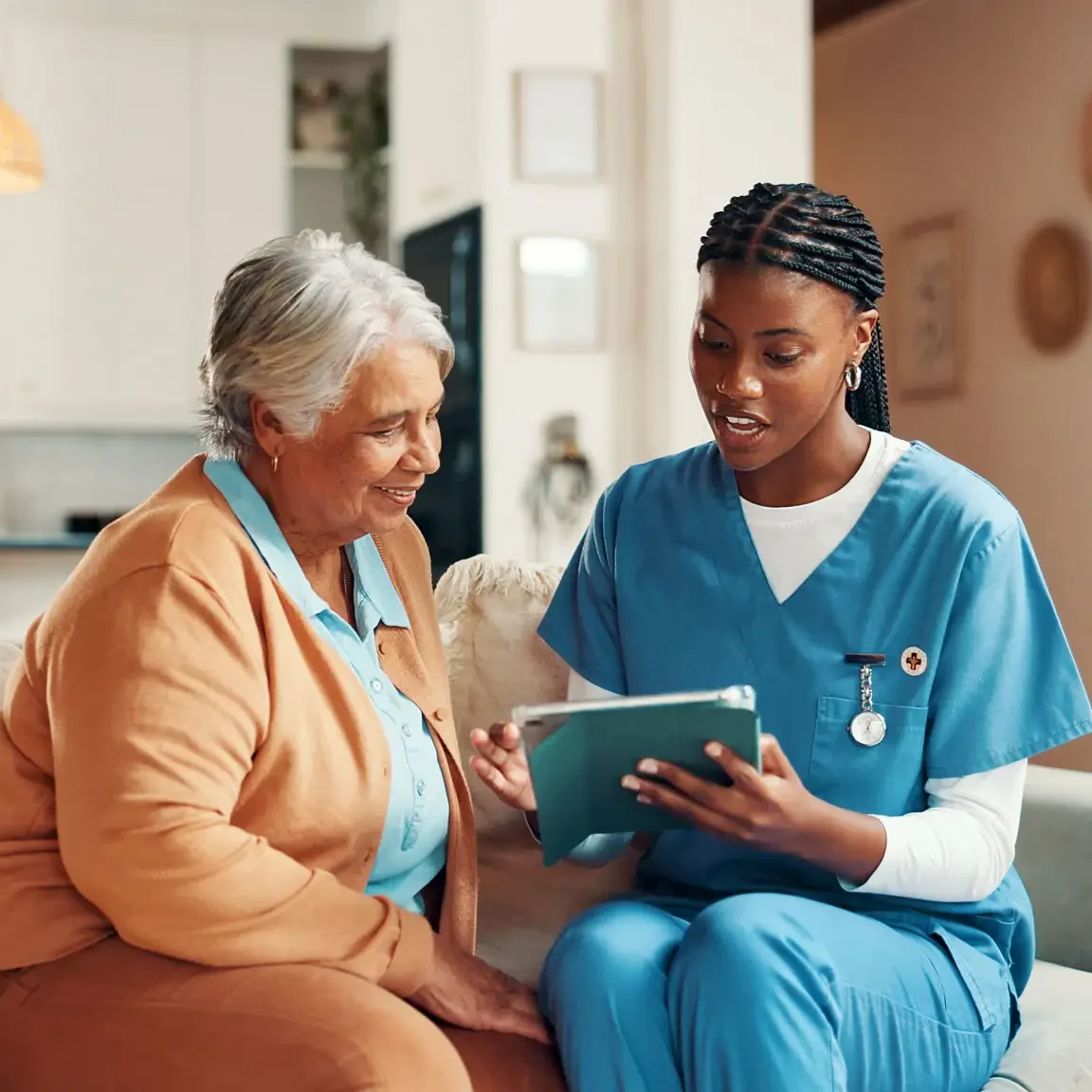 Caregiver showing tablet to elderly woman